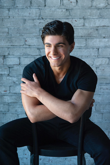 alt="Aaron Ventresca smiling while sitting on a chair."