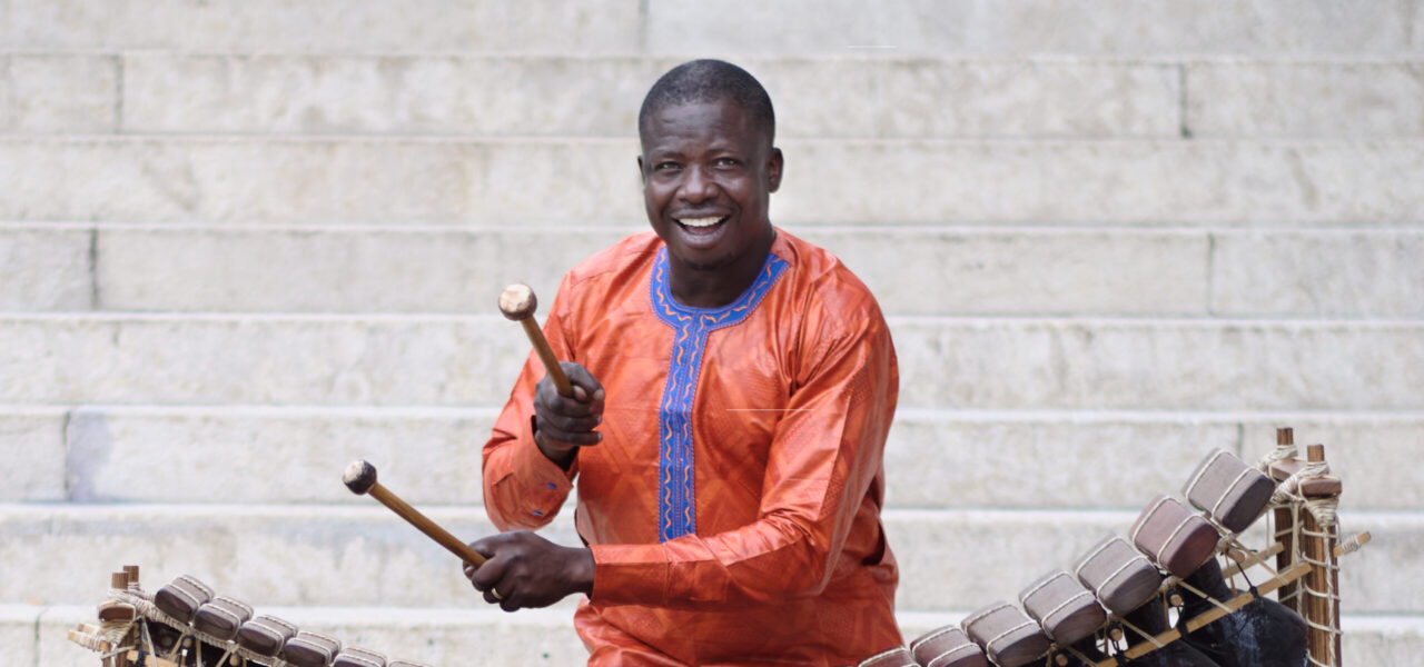 Mamadou Diabate smiling and playing an instrument