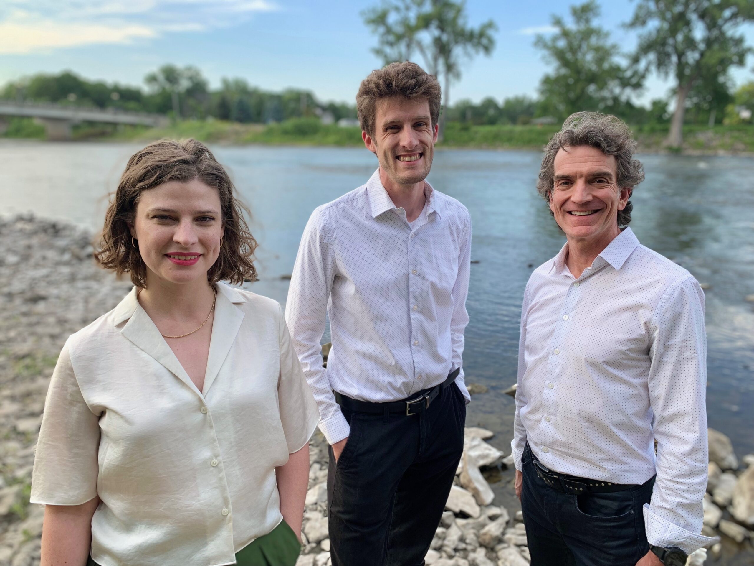 Three people standing in front of a body of water
