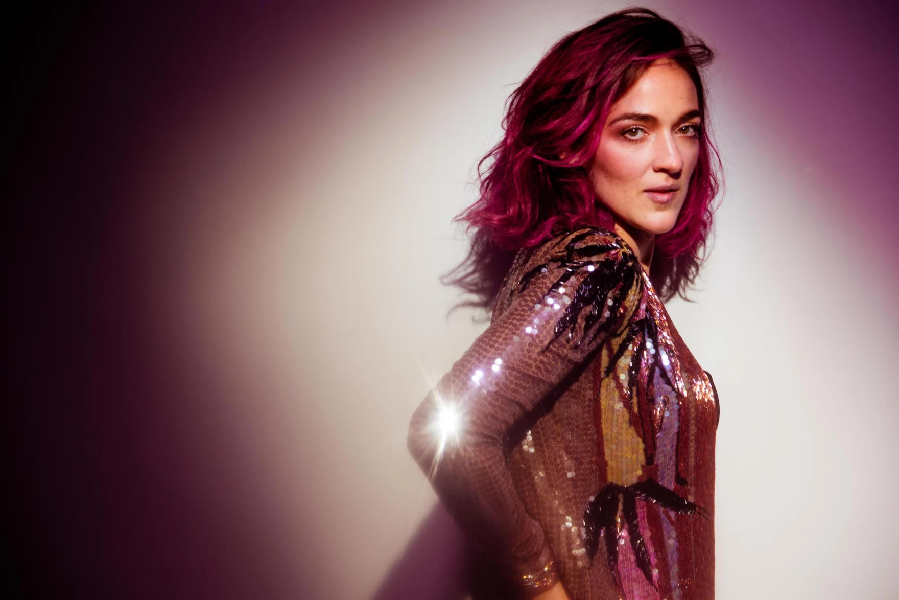 Portrait of woman in shiny outfit and purple background