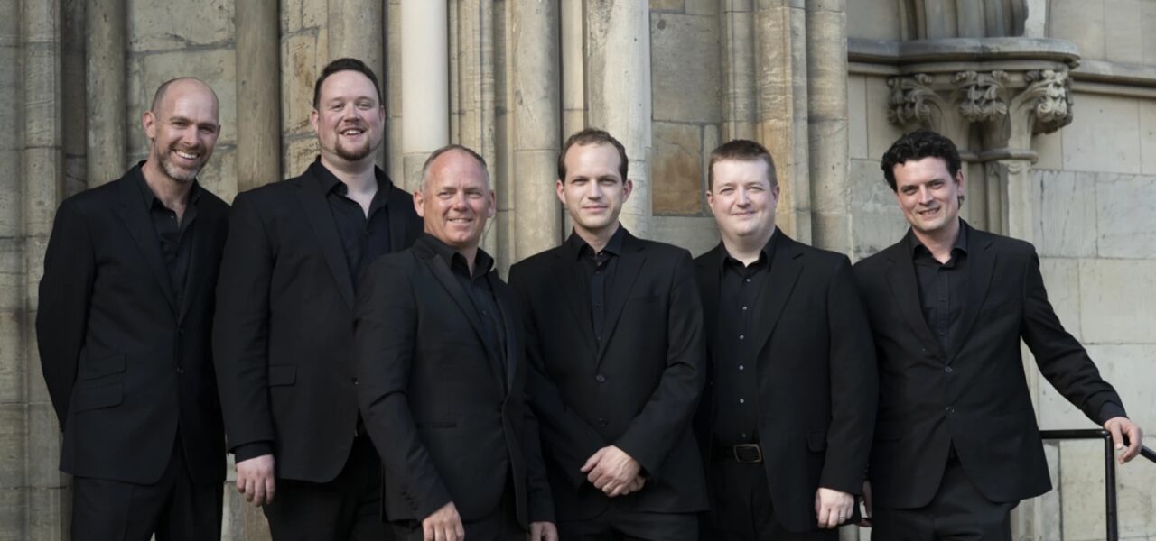 A group of musicians wearing black suits outside in front of a building in Princeton