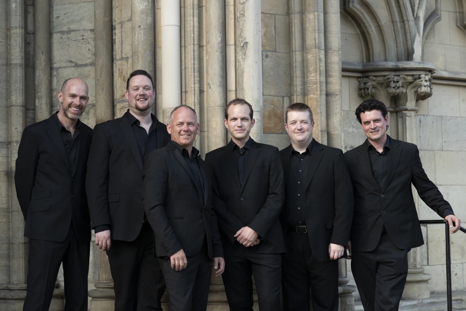 A group of musicians wearing black suits outside in front of a building in Princeton