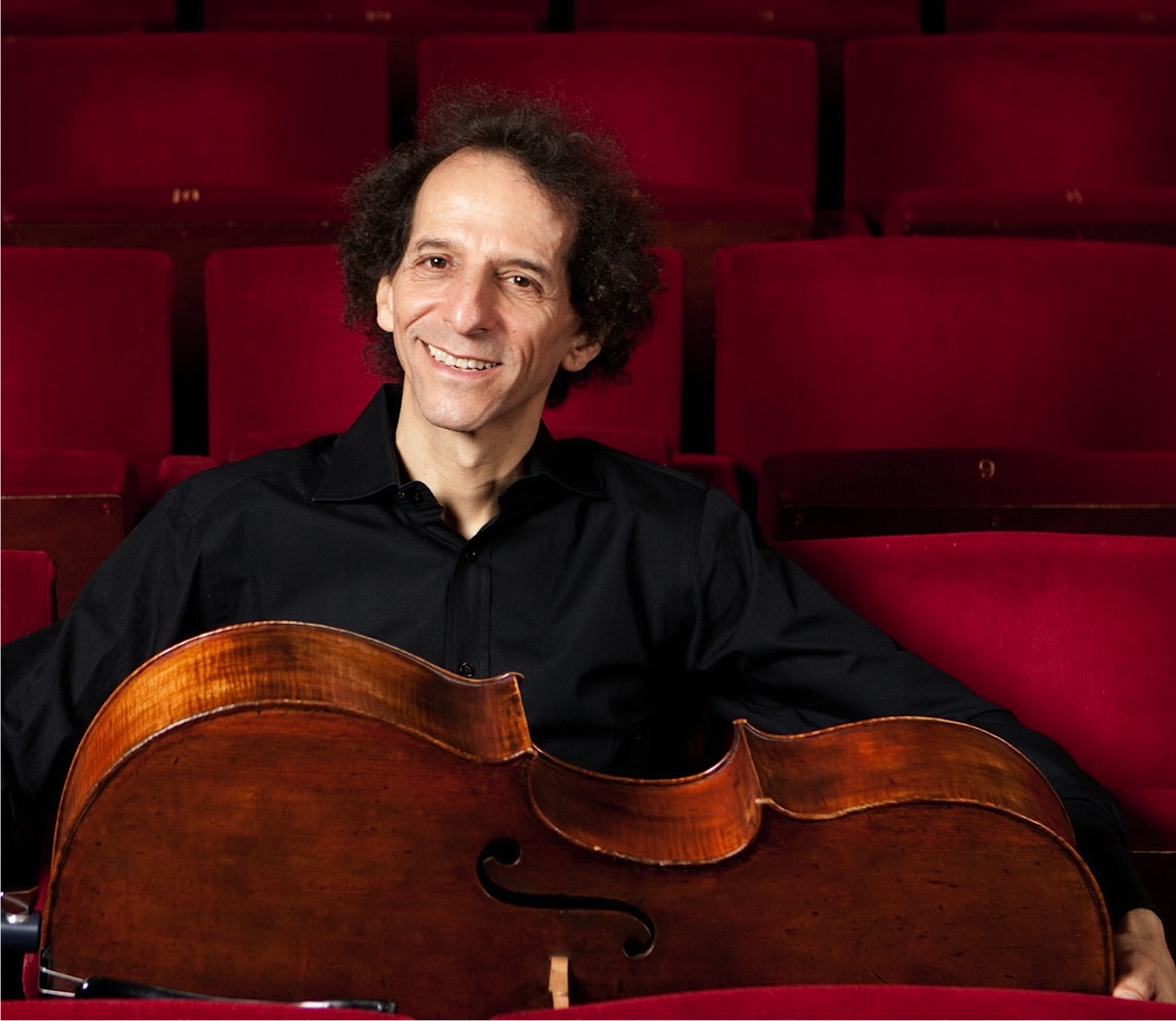 A person sitting in a theater holding a cello